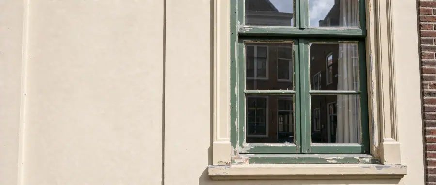Historisch houten raam met groene en crèmekleurige verf aan een Arnhemse stadsgevel